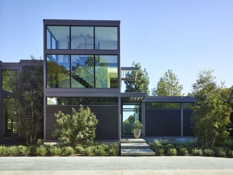siyah metal yapıdan yapılmış ev, cam duvarlar, çalılar ve merdivenlerle bahçe