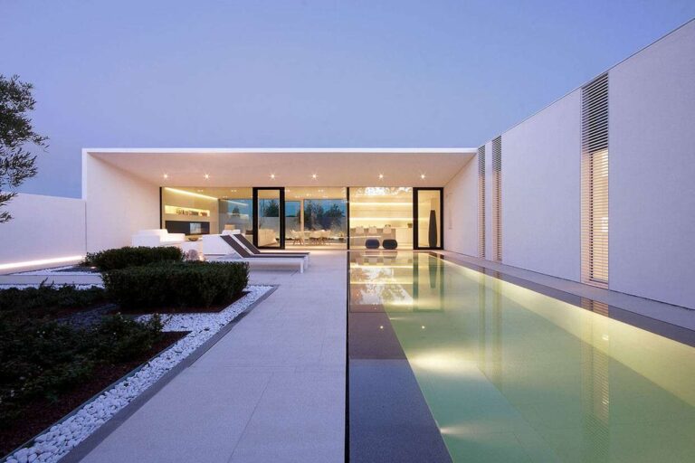 arka planda aydınlatmalı büyük uzun havuz cam duvarlı modern ev