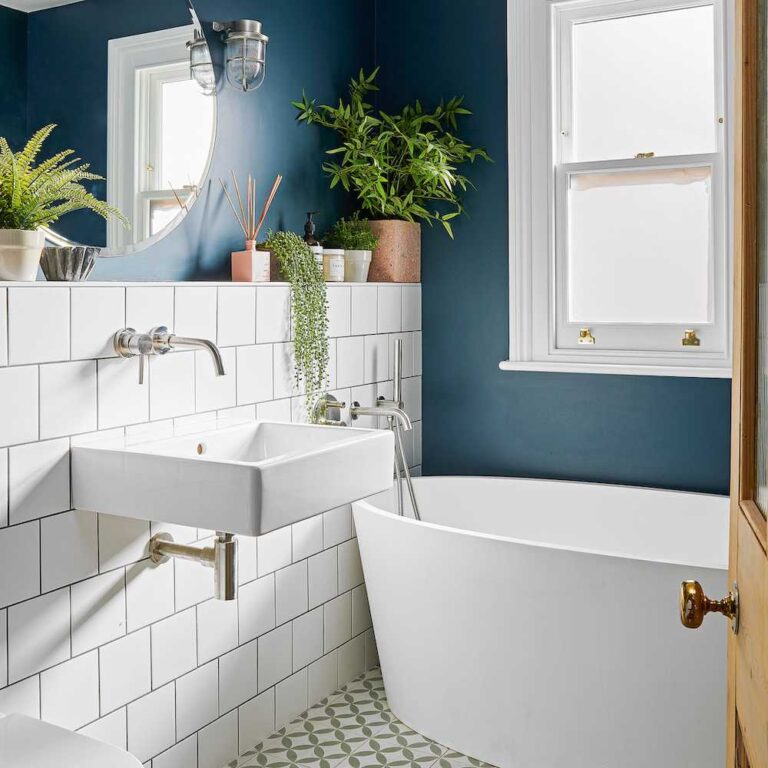 Bitkiler, beyaz fayanslar ve mavi duvarla süslenmiş raflı banyo